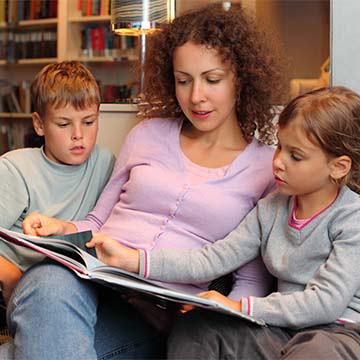 A mother reading a book to two children