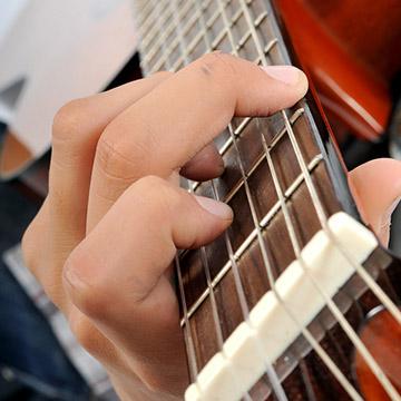 A close up photo of someone strumming and acoustic guitar