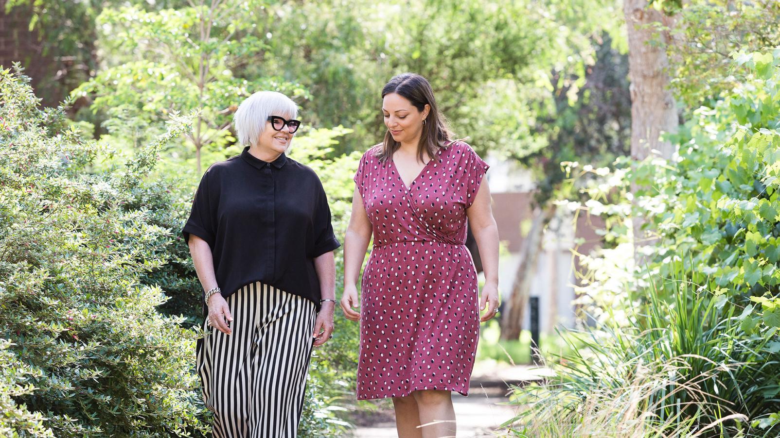 Two females walking in a garden and chatting