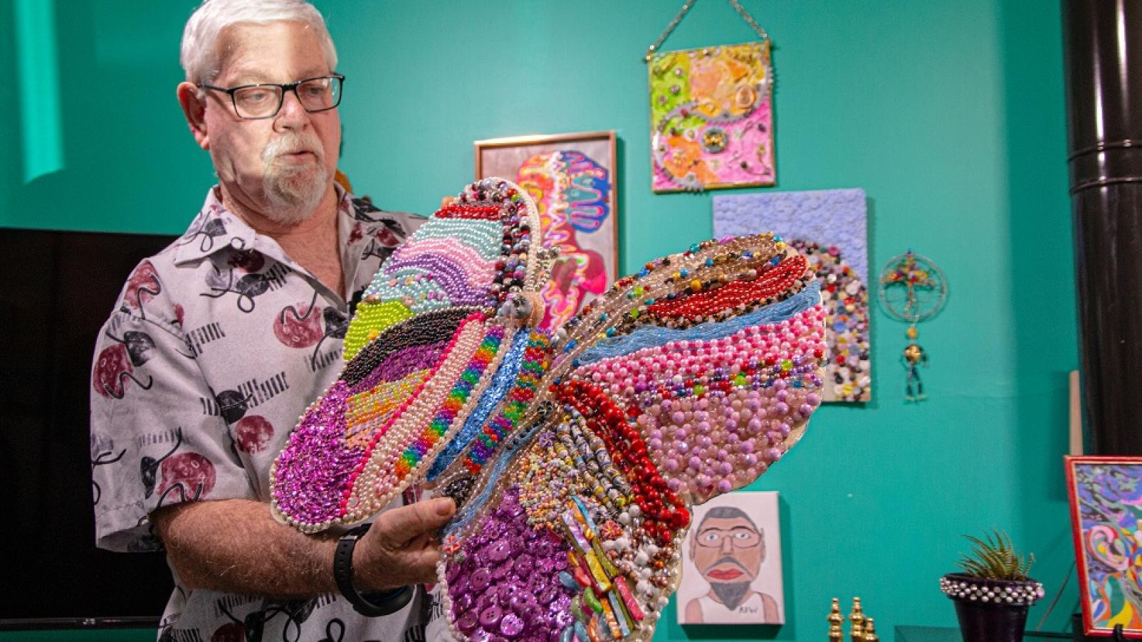 A man holding some sort of home made artwork resembling a butterfly