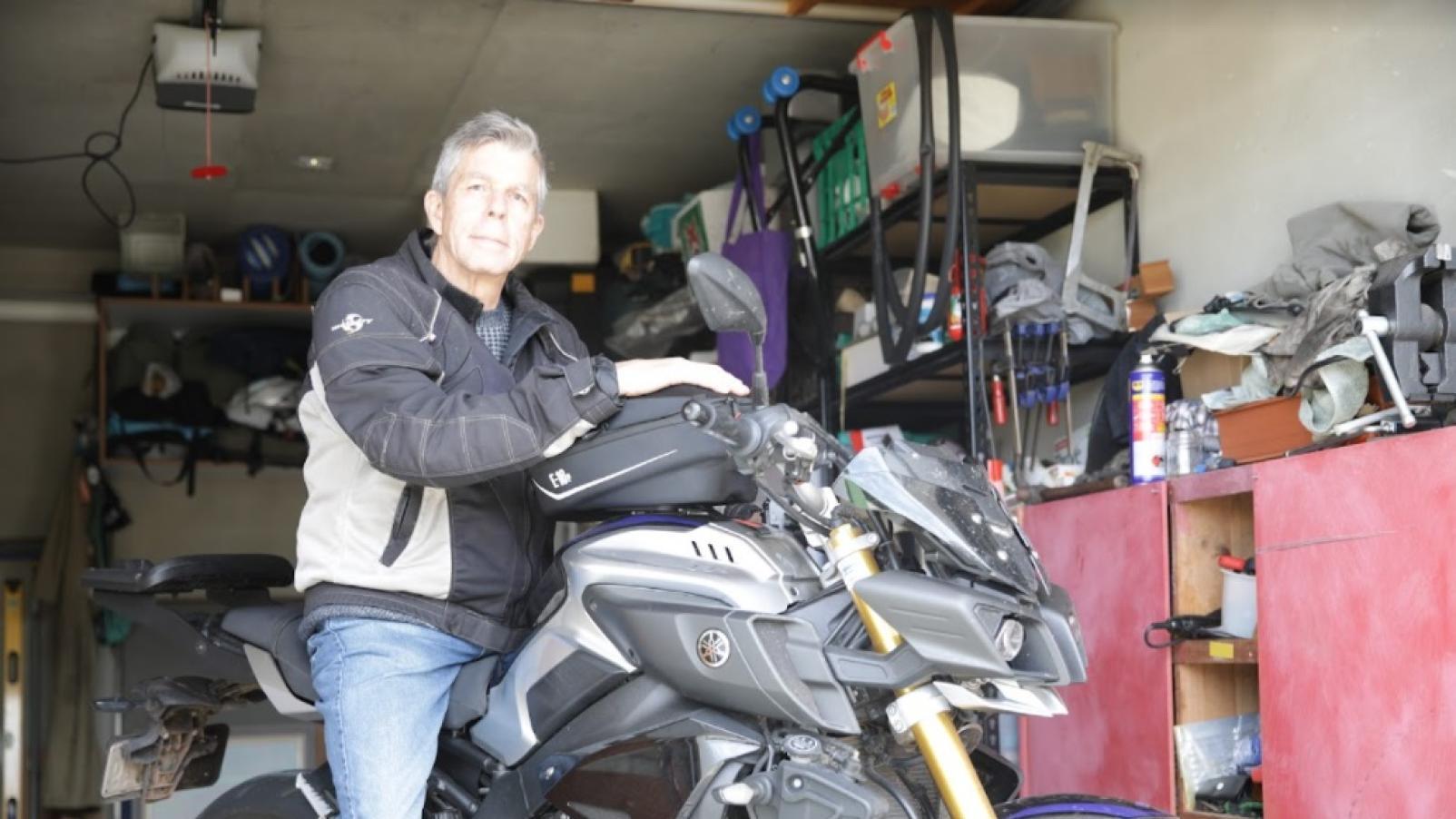 A man wearing motorcycle safety clothing sitting on his bike in his garage