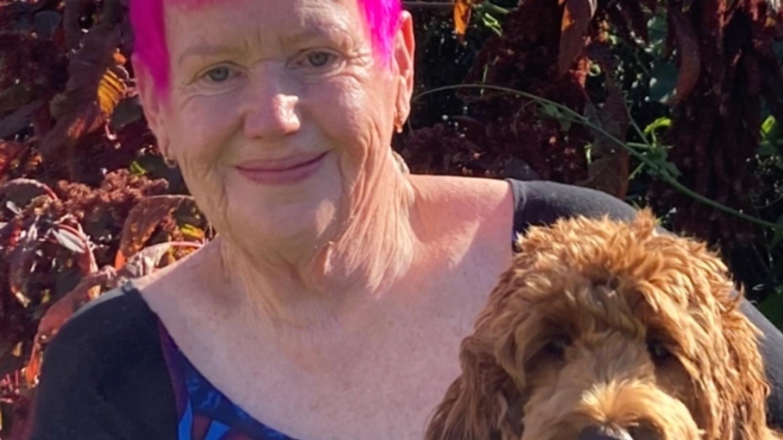 Dementia Advocate Gwenda Darling holding her dog in the sunshine..