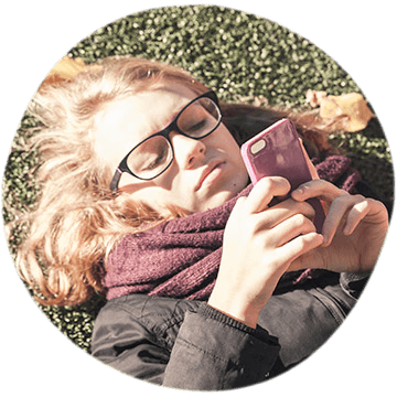 A young female laying on the grass looking at her phone