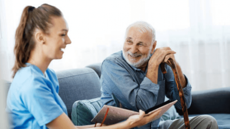 A female aged care worker showing a photo album to an elderly man.