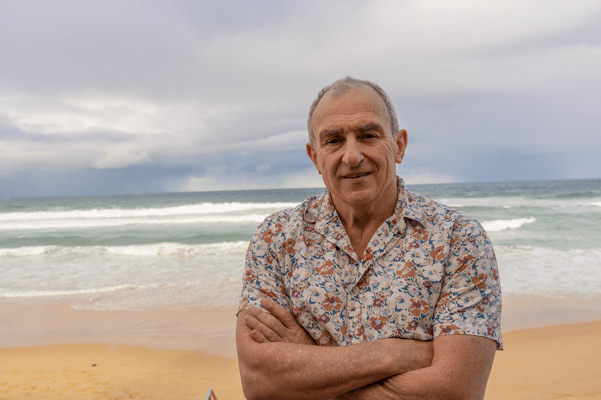 Dementia Advocate Bill Yeates standing on a beach and smiling at the camera