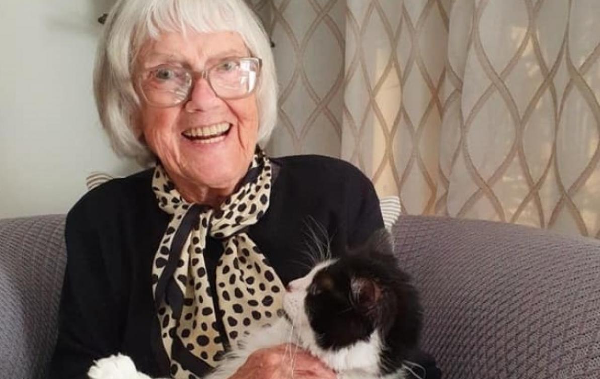 Oma sitting on a sofa and holding her cat Hailey.