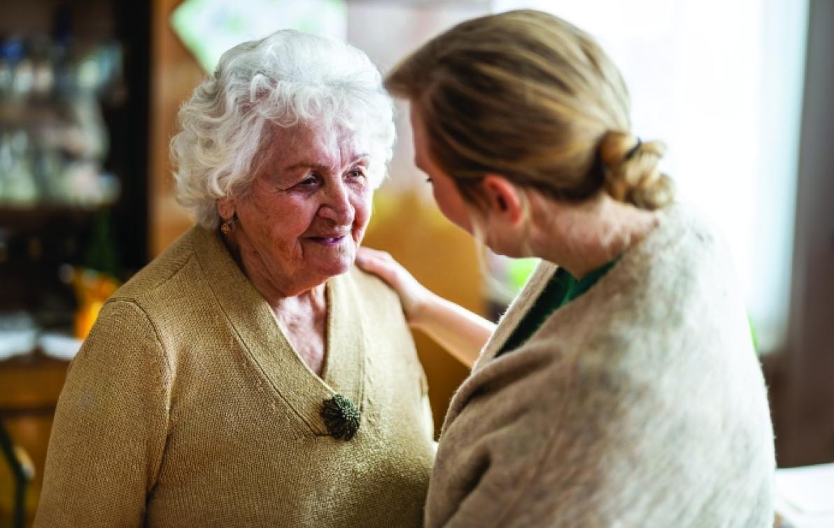 An aged care worker tending to an elderly woman.