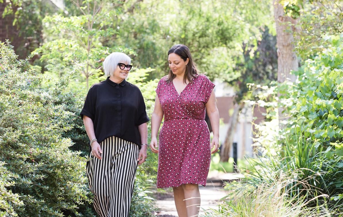 Two females walking in a garden and chatting
