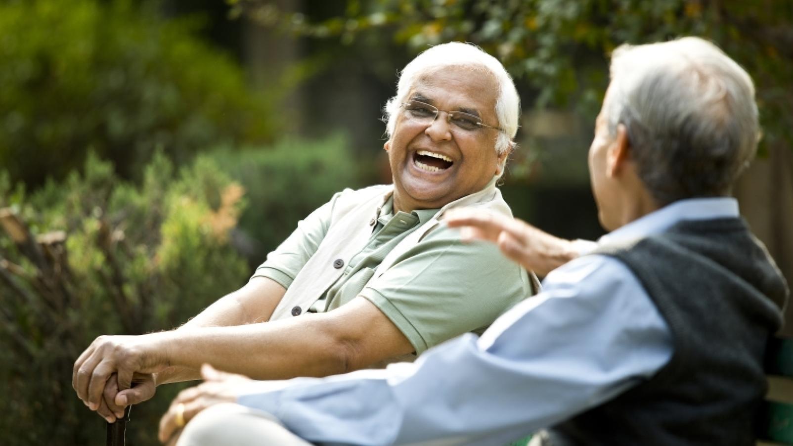 Two elderly friends share a laugh in the park