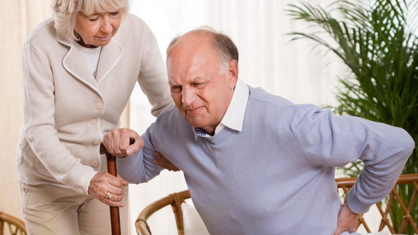 Elderly man with back pain being assisted by his wife
