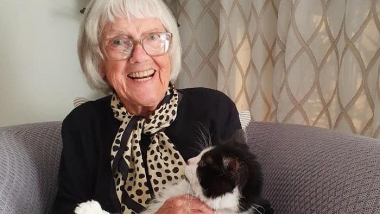 Oma sitting on a sofa and holding her cat Hailey.