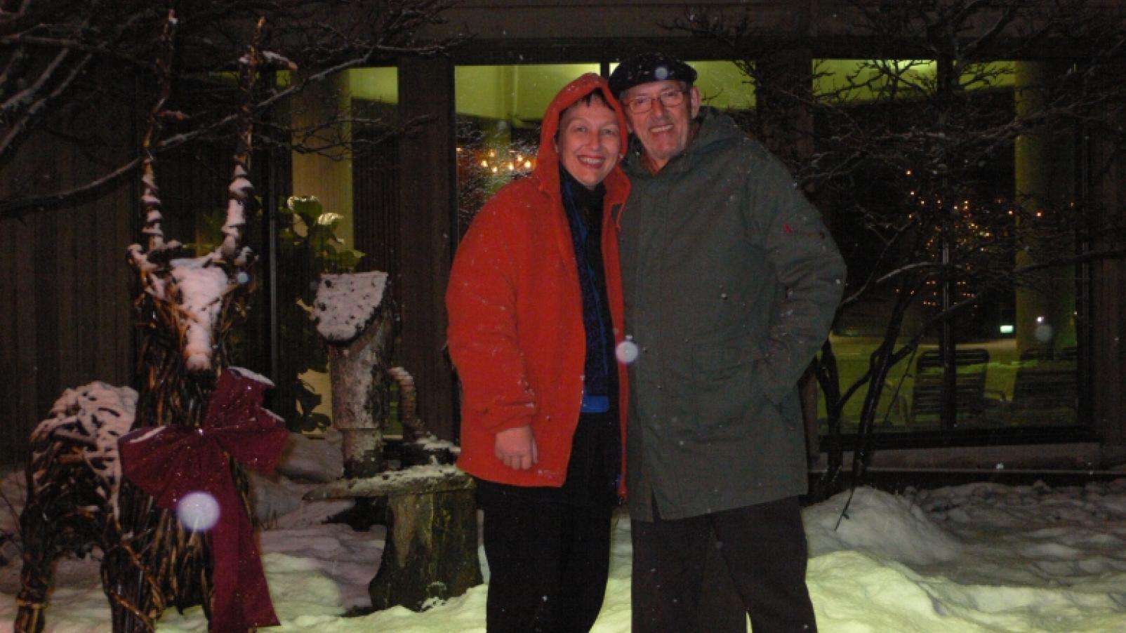 Kay and her husband Richard, posing outside at night in a snowy location.