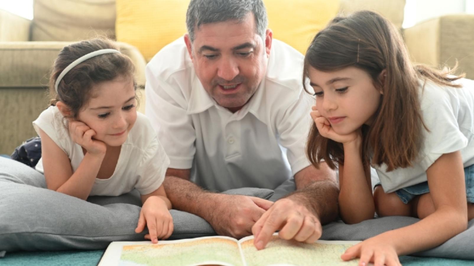 a father reading to his daughters