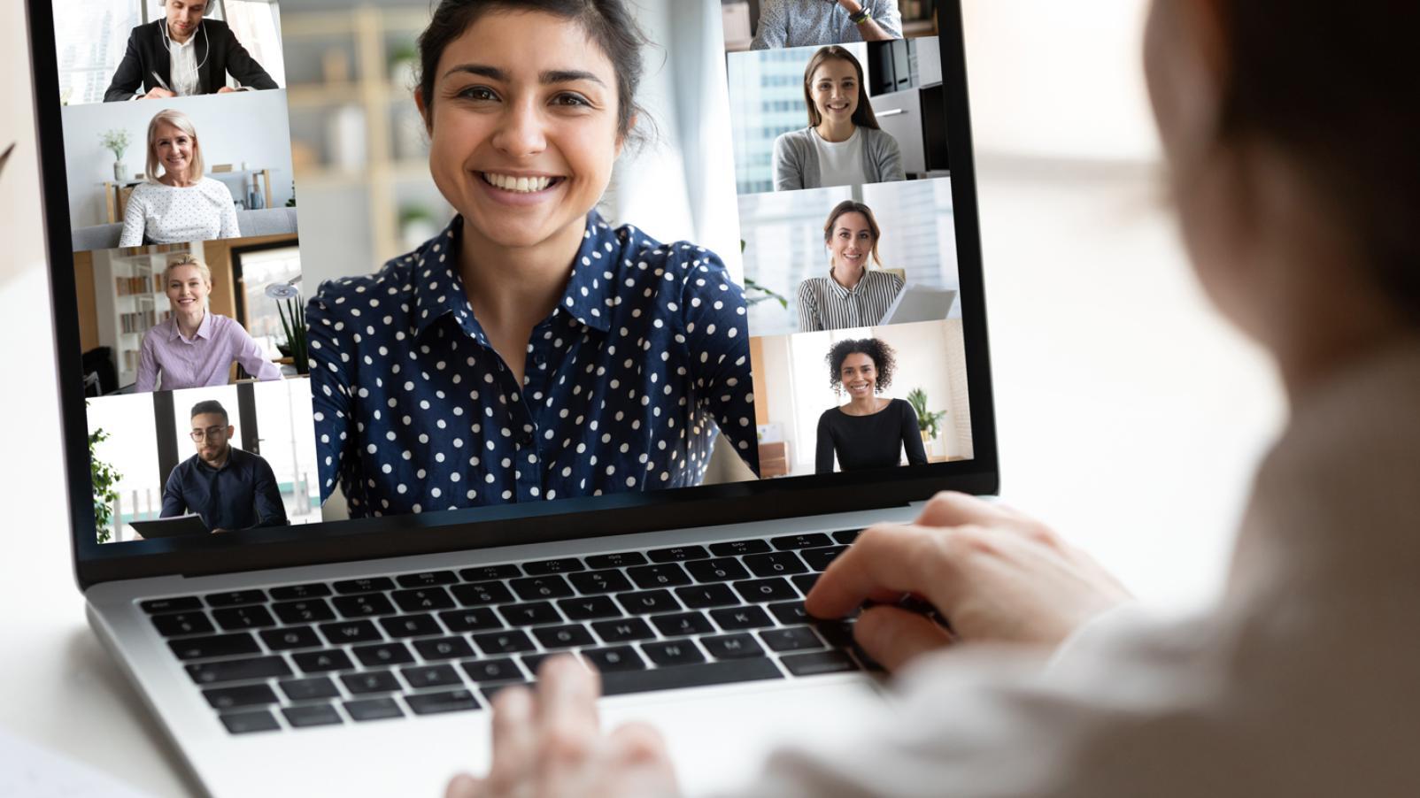A person sitting at their laptop on a video call with several people
