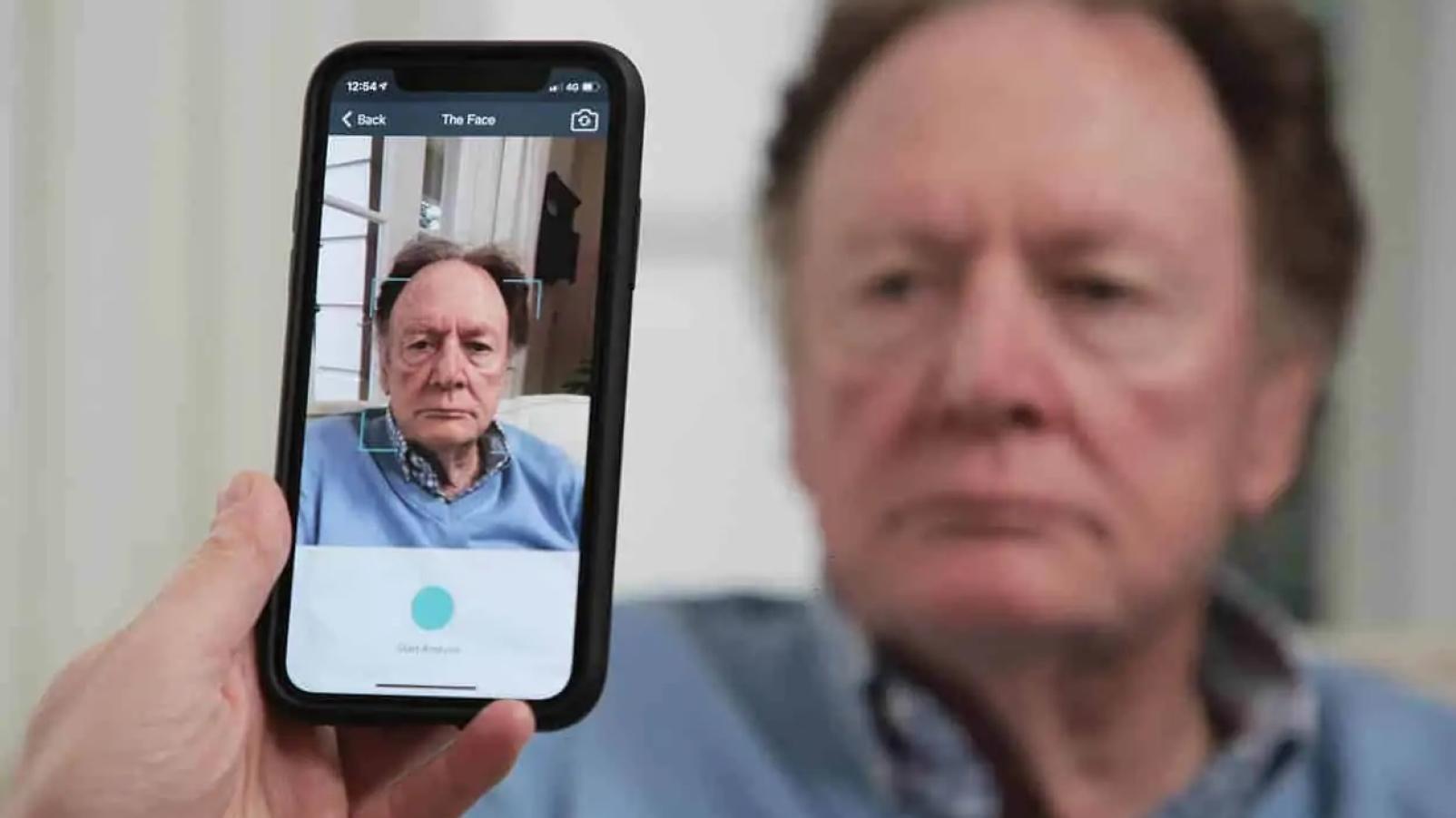 The PainChek app on a phone analyses the face of an older man