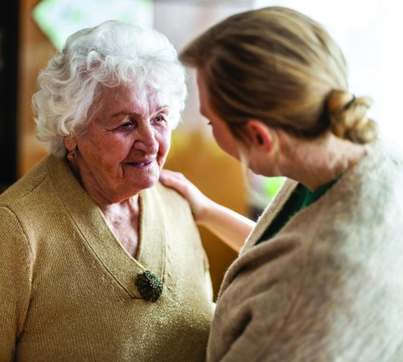 An aged care worker tending to an elderly woman.