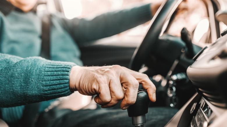 A driver's hand firmly on the gear stick of a vehicle.